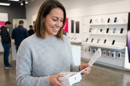 Jeune femme tenant un smartphone neuf et son contrat dans une boutique d'opérateur mobile
